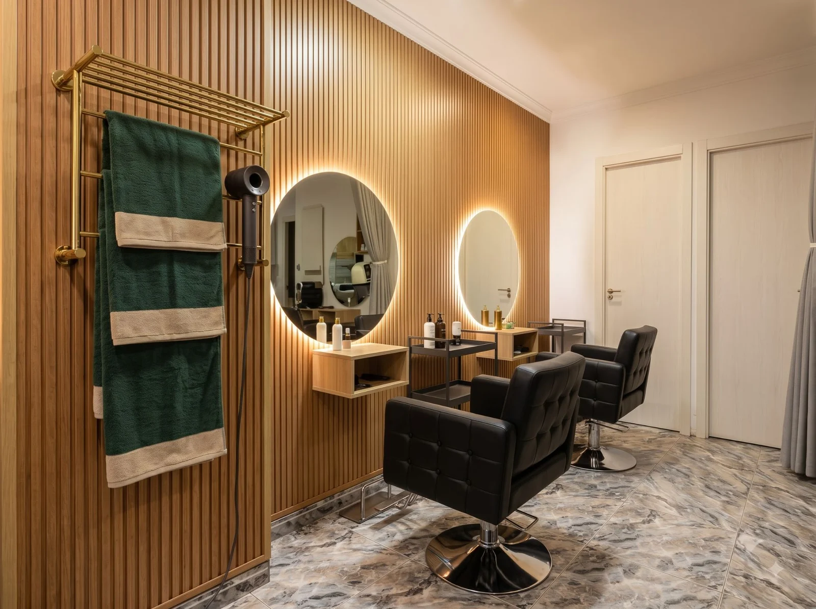 Puestos de peinado del salón Domenech, con espejos retroiluminados y pared de listones de madera